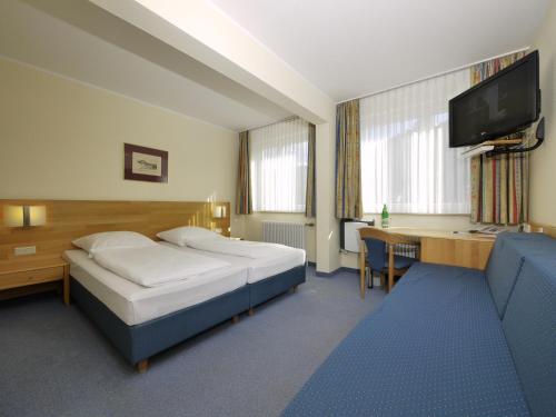 Habitación de hotel con 2 camas y escritorio en Hotel Pinger en Remagen