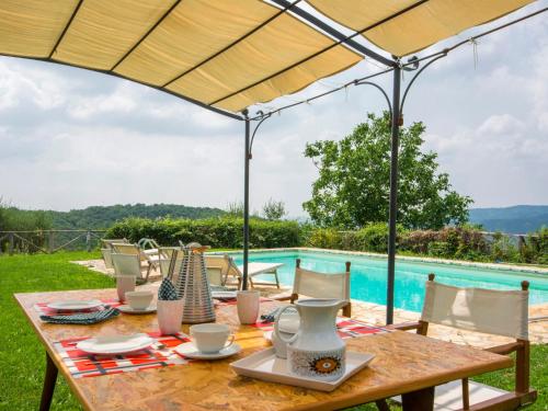 un tavolo in legno con sedie e ombrellone accanto alla piscina di Holiday Home Villa La Piaggia by Interhome a San Pancrazio