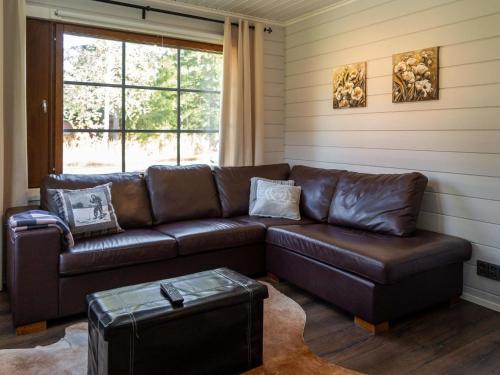 ターコブオリにあるHoliday Home Tahkovuorentie 34 a by Interhomeの窓付きの客室で、茶色の革張りのソファが備わります。