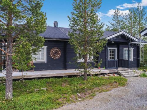 a black house with a porch and trees at Holiday Home Tuulenpuuska by Interhome in Äkäslompolo