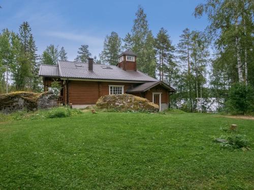 ein Blockhaus auf einem grünen Rasen in der Unterkunft Holiday Home Hiidenlinna by Interhome in Pitkälahti