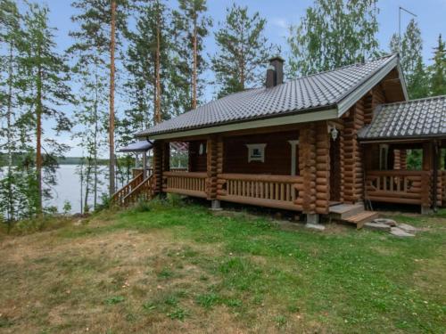 una cabaña de madera en el bosque con un lago en Holiday Home Neitlinna by Interhome, en Pitkälahti