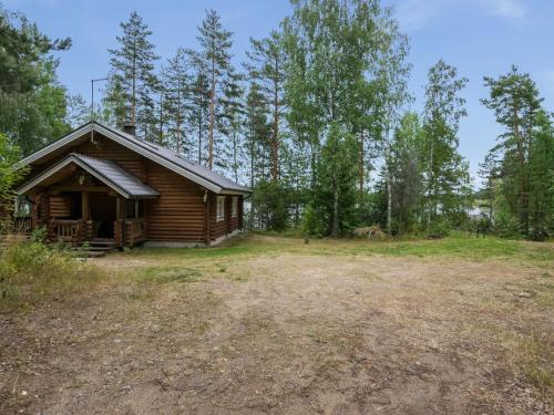 una cabaña de madera en el bosque al lado de un campo en Holiday Home Neitlinna by Interhome, en Pitkälahti