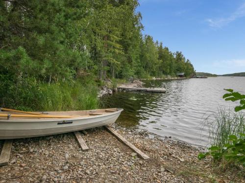 a boat sitting on the shore of a lake at Holiday Home Neitlinna by Interhome in Pitkälahti