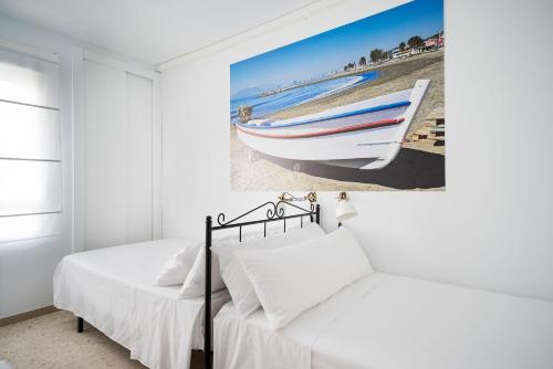 1 dormitorio con 2 camas y una pintura de un barco en Arcos Beach Infostays - Free Parking, en Málaga