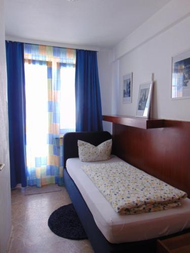 a bedroom with a bed and blue curtains at Hostel Heinzelmännchen in Cologne