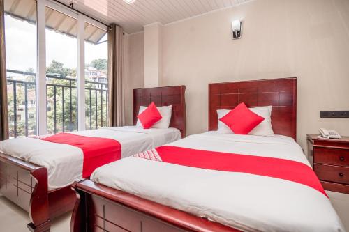 two beds with red pillows in a room with a window at Janora Hills in Kandy