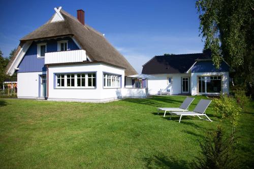 a white house with a thatched roof and a bench in the yard at Haus Meerblau in Born