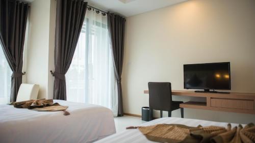 a hotel room with two beds and a desk with a television at Picnic Hotel Bangkok - Rang Nam in Bangkok