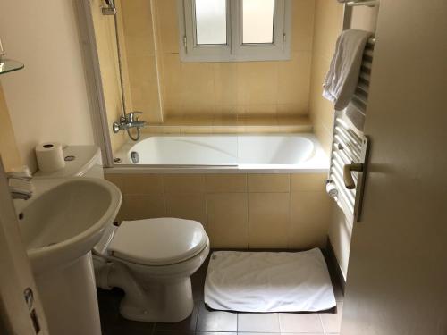 een badkamer met een bad, een toilet en een wastafel bij Hotel des Bains in Maisons-Alfort