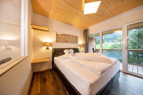 ein großes Bett in einem Zimmer mit einem großen Fenster in der Unterkunft Hotel Post Krimml in Krimml