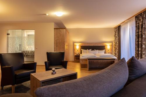 a hotel room with a bed and a couch and chairs at Hotel Dirsch Wellness & Spa Resort in Emsing