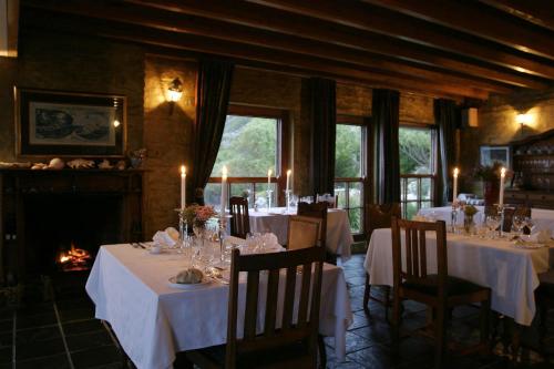 comedor con mesas y sillas blancas y chimenea en Agulhas Country Lodge, en Agulhas