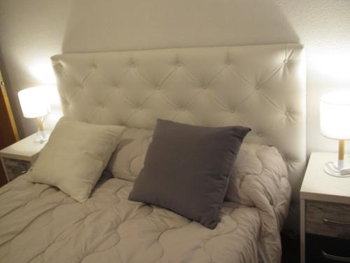 1 cama con cabecero blanco y almohada en Apartamento Avenida, en Cuenca