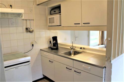 a small kitchen with a sink and a microwave at 6-pers vakantiebungalow in het Heuvelland in Simpelveld