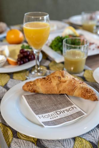 a table with a plate of food and orange juice at Hotel Dirsch Wellness & Spa Resort in Emsing