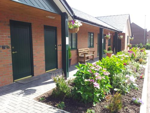 a row of houses with green doors and flowers at Deangate Motel in Lydney