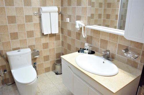 ein Badezimmer mit einem weißen WC und einem Waschbecken in der Unterkunft Capital Hotel Djibouti in Dschibuti