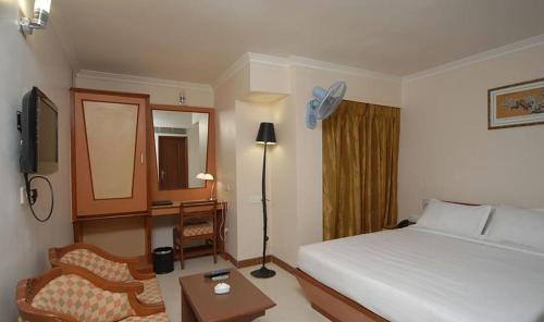 a hotel room with a bed and a chair and a desk at Epsilon Hotel in Ahmedabad