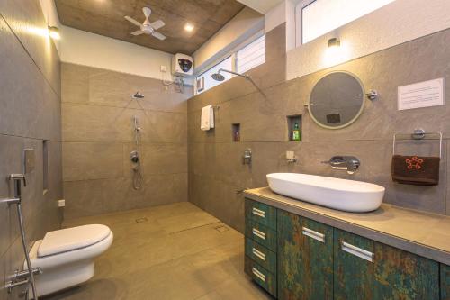 y baño con lavabo, aseo y espejo. en SaffronStays Serenity, Igatpuri en Igatpuri