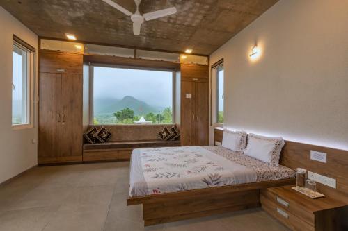 a bedroom with a bed and a large window at SaffronStays Serenity, Igatpuri in Igatpuri