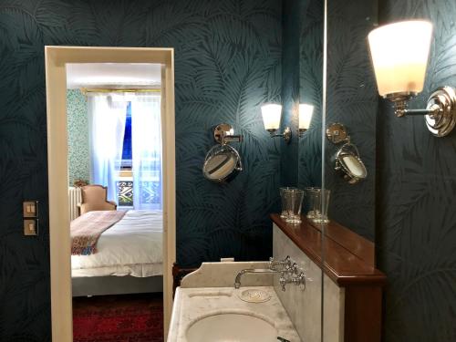 een badkamer met een wastafel, een spiegel en een bed bij Le 48 Paris in Parijs