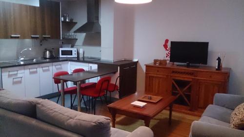 a living room with a couch and a table and a kitchen at Apartamentos Laurel in Logroño