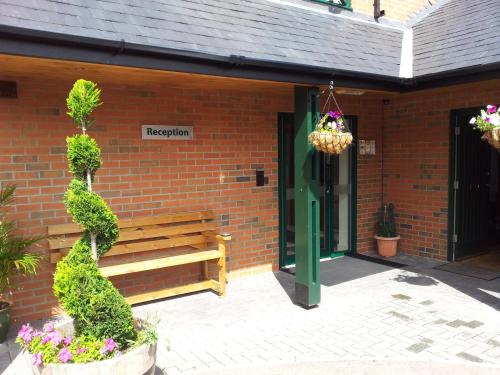 a brick building with a wooden bench in front of it at Deangate Motel in Lydney