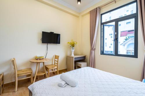 a bedroom with a bed and a window and a table at Maison Royale in Ho Chi Minh City