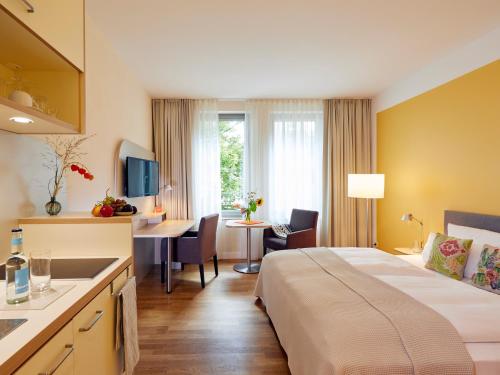 ein Hotelzimmer mit einem großen Bett und einem Schreibtisch in der Unterkunft Flottwell Berlin Hotel & Residenz am Park in Berlin