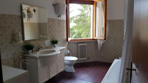 Un baño con lavabo, inodoro y ventana. en VAL D'ORCIA DELUXE 1 ELEGANTE CASA immersa nel verde con WiFi, giardino e parcheggio, en San Giovanni dʼAsso