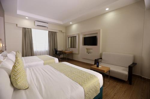 a hotel room with two beds and a chair at PrideInn Plaza Nairobi Airport in Nairobi