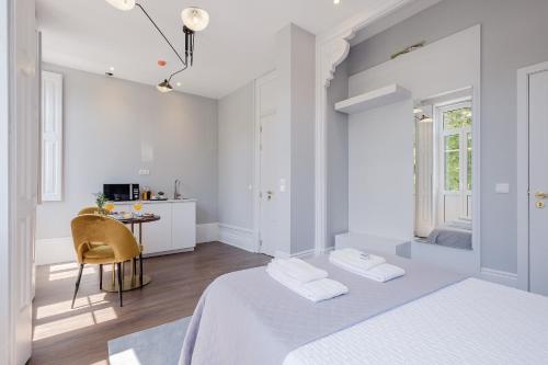 a white bedroom with two beds and a table at Plaza-Charming GuestHouse in Porto