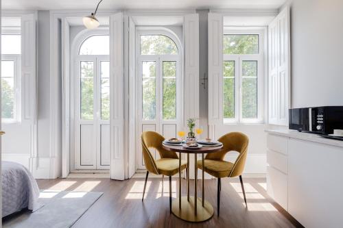 a white kitchen with a table and two chairs at Plaza-Charming GuestHouse in Porto