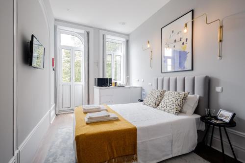 a white bedroom with a bed and a table at Plaza-Charming GuestHouse in Porto