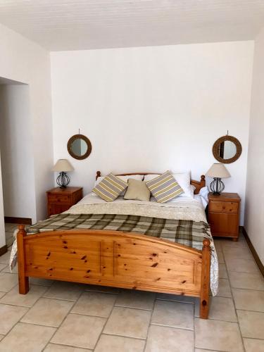 - une chambre avec un lit en bois et 2 miroirs sur le mur dans l'établissement La Banne Nord, à Cendrieux