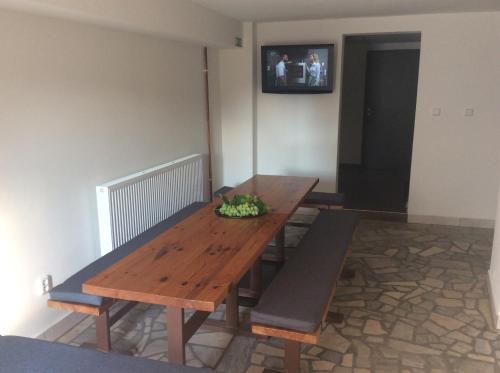 drewniany stół i ławki w pokoju z telewizorem w obiekcie Vinný sklípek Na Spojovací w mieście Mutěnice