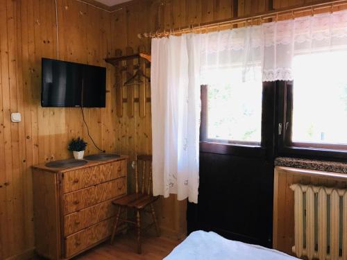 a bedroom with a bed and a television and a window at Willa Anna in Kościelisko