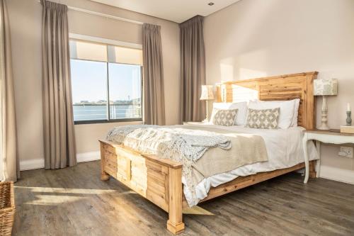 a bedroom with a bed and a desk and a window at Luxury Ocean View 2 Bed Apartment 259 Eden on the Bay, Blouberg, Cape Town in Big Bay
