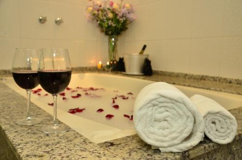 a bath tub with two glasses of wine and roses at Hotel Fazenda Hípica Atibaia in Atibaia