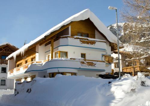 ein mit Schnee bedecktes Haus mit einem Schneehaufen in der Unterkunft Apart Bergblick in Ischgl