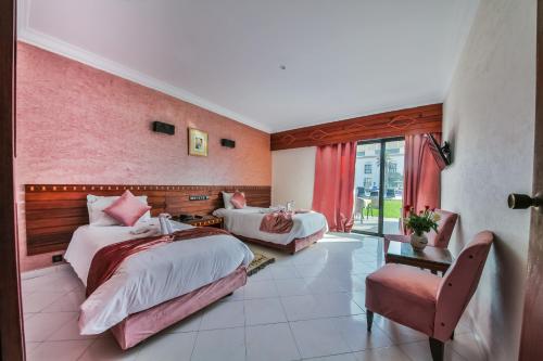 a hotel room with two beds and a chair at Hôtel Des Iles in Essaouira