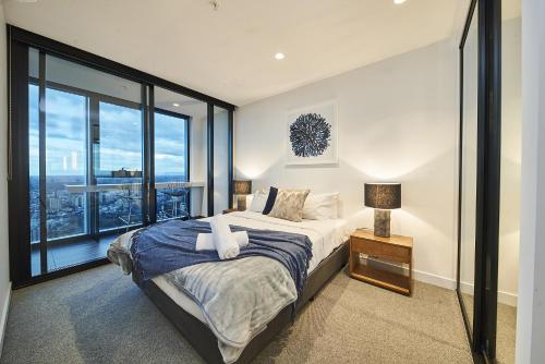 a bedroom with a bed and a large window at Mega Style Apartments Victoria One in Melbourne