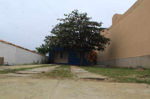 a tree in front of a building with a blue door at Temporada no Paraíso in Ilha Comprida