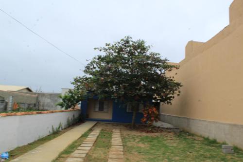 a tree next to a building with a blue door at Temporada no Paraíso in Ilha Comprida