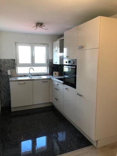 uma cozinha com armários brancos, um lavatório e um frigorífico em Ferienwohnung Albblick 3 Münsingen em Münsingen