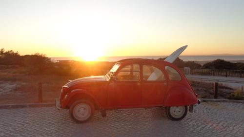 a small red car parked in front of the sunset at Casa Férias Melides in Melides