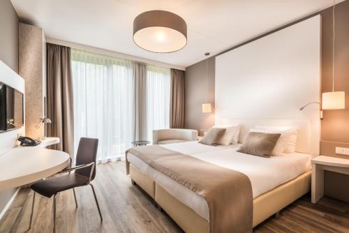 ヴァーヘニンゲンにあるFletcher Hotel-Restaurant de Wageningsche Bergの大きなベッドとデスクが備わるホテルルームです。