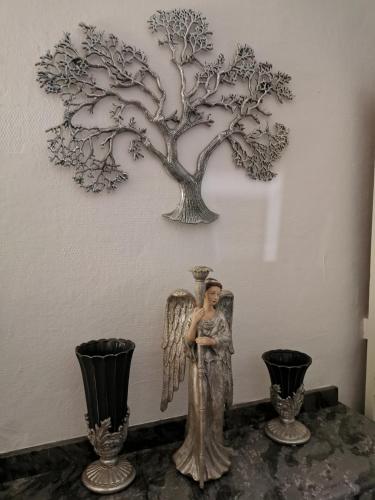 a statue of an angel next to a tree on a wall at Château de Verdalle in Verdalle
