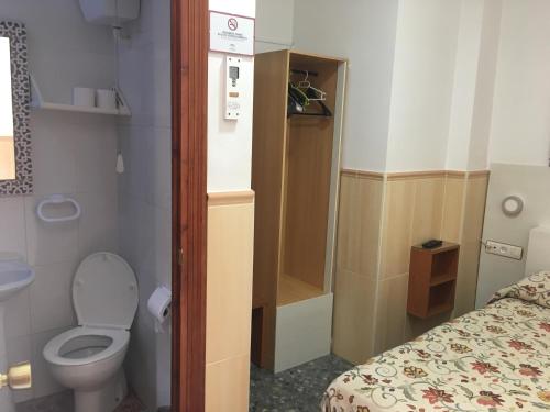 a small bathroom with a toilet and a bed at Pensión El Hidalgo in Granada